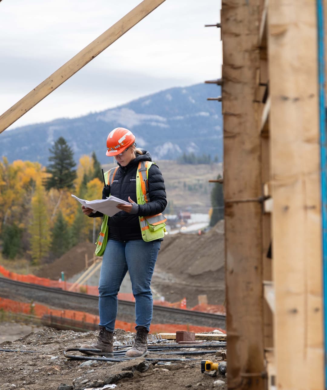 A woman on a construction site reading a blueprint